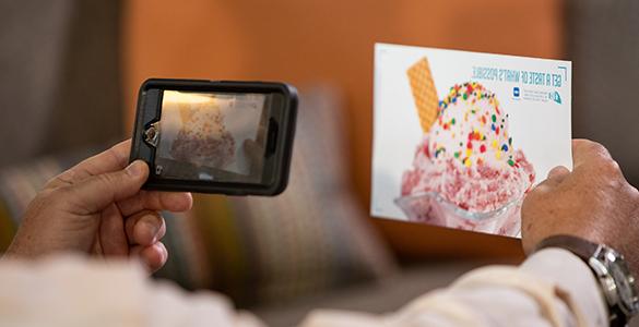 Image of a person taking a picture of a direct mail piece.